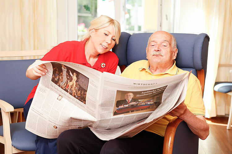 Pflegerin liest zusammen mit einem alten Herren die Zeitung - 2013